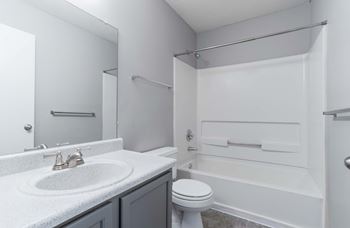 A white bathroom with a toilet, sink, and bathtub.